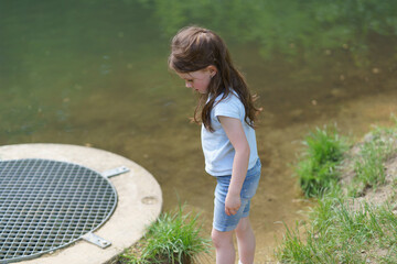 Little cute sad girl walking in summer park. Concept of sad child outdoors