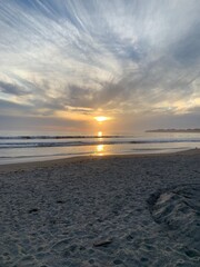 This breathtaking image showcases a beautiful beach sunset, with the golden hues of the setting sun reflecting on the gentle waves of the ocean. 