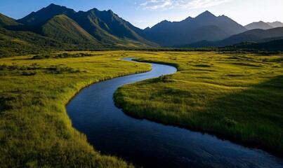 Serpentine river meandering through a verdant valley, nestled amidst majestic mountains under a clear sky.