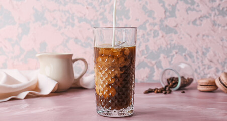 Pouring of milk into glass with hot coffee on color background