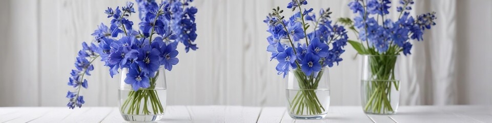 Fresh blue delphinium flowers in a clear glass vase on a white wooden table, garden blooms, blue flowers vase, home decor inspiration