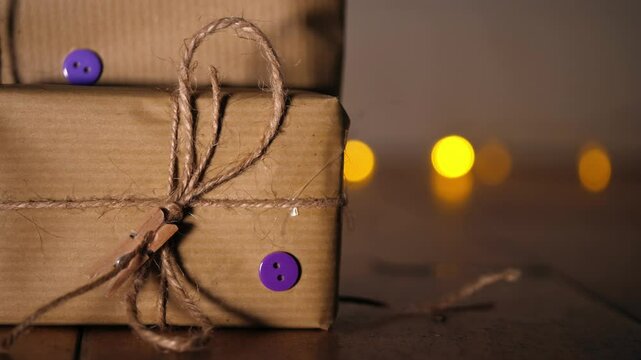 Gift wrapped in brown paper and string with Christmas lights bokeh background