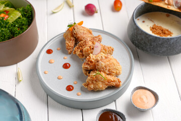 Crispy fried chicken with sauce and salad side and Mushroom soup bowl, white wood background