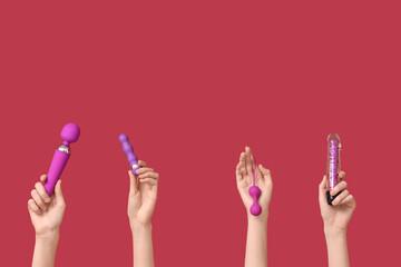 Female hands with vibrators and vaginal balls on red background