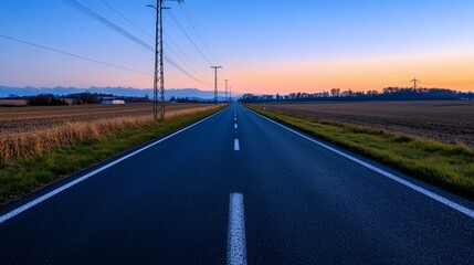 Fototapeta premium Empty asphalt road at sunset, leading to distant mountains.