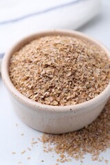 Buckwheat bran in bowl on white table, closeup