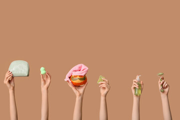 Women holding funny pumpkin with under-eye patches, cosmetic products and accessories on color background