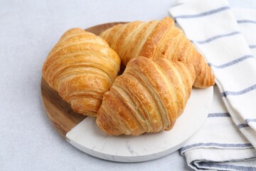 Tasty fresh croissants on light grey table, closeup