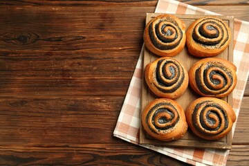 Tasty buns with poppy seeds on wooden table, top view. Space for text