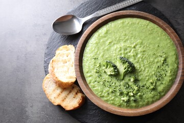 Delicious broccoli cream soup served on grey table, flat lay