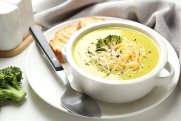 Delicious broccoli cream soup served on white wooden table, closeup