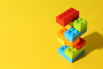 Construction toy. Figure made with building bricks on yellow background, space for text