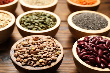 Different superfood products in bowls on wooden table, closeup