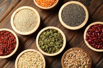 Different superfood products in bowls on wooden table, flat lay