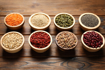 Different superfood products in bowls on wooden table