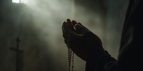 Hands holding a rosary in a dimly lit space.