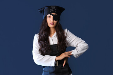 Beautiful young Asian woman dressed as pirate on dark blue background