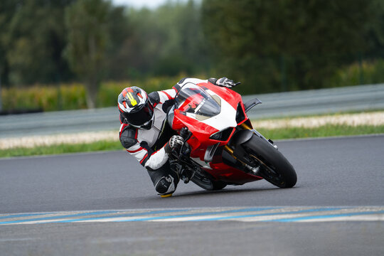 A motorcycle rider riding on a red sport motorcycle through a corner at high speed. Leaning from the bike and dragging a knee.	
