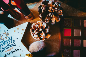 Lipstick, bumps, eye shadow palette, blush palette, star and makeup brushes on golden paper background
