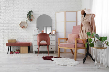 Stylish interior of light room with dressing table and beautiful dress on mannequin
