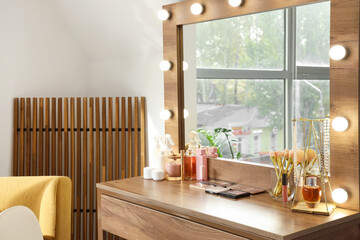 Wooden dressing table with different cosmetics and accessories in room
