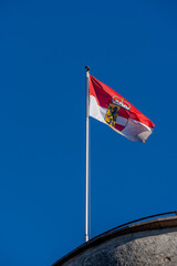 Austria flag blows in the wind on a clear day, taken at Fortress Hohensalzburg