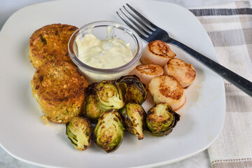 two crab cakes served with sheared scallops