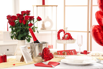 Table setting with red roses and bottle of wine. Valentine's Day celebration