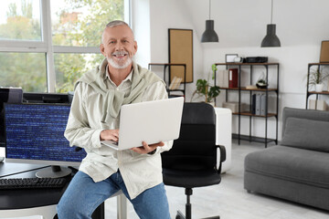 Mature programmer working with laptop in office
