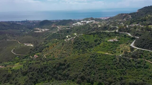 Countryside of Spain. View of area between Marbella and Ojen. Hills with different fields of agriculture. Small farms. In background is Mediterranean Sea and Marbella city. Costa del Sol. Drone forwar
