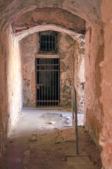 Fototapeta premium An aged hallway with a barred door in Priamar Fortress, showcasing historical architecture and atmospheric decay, perfect for themes of preservation and history.