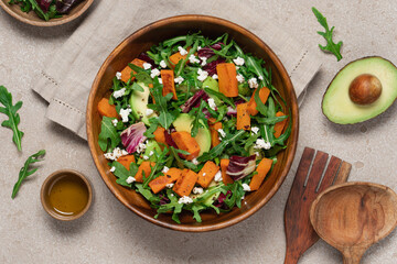 Sweet potato salad with arugula, avocado, cucumber and veta cheese in wooden bowl on light background. Healthy food top view. Food background with copy space