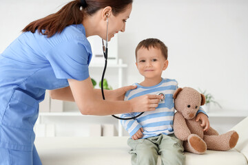 Female pediatrician with stethoscope listening to cute little boy in clinic