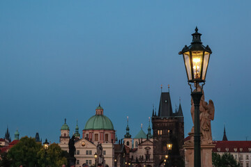 Obraz premium Scenic view of iconic Charles Bridge, Old Town Prague, Czechia. Gothic Old Town Bridge Tower at night in summer. Baroque dome of Church St. Francis of Assisi in background. Street lanterns illuminated