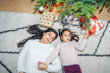 The family enjoys quality time near the decorated Christmas tree. The children unwrap presents,...