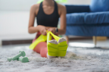 Woman performs stretching exercises with a resistance band, focusing on leg and core strength in her living room