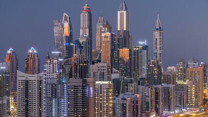 Naklejka premium Dubai marina with traffic on sheikh zayed road panorama day to night timelapse lights turn on.