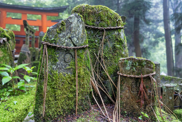 Sacred stones wrapped with rope (Yorishiro) at Fushimi Inari Taisha temple in Kyoto, Japan. ( Translation of the japanese text: religion blessings)