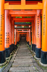 The torii gate covered walking path at Fushimi Inari Taisha temple in Kyoto, Japan. ( Japanese inscriptions translated are different religion blessings)