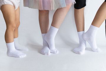 three pairs of children's feet in light and dark socks on a white background