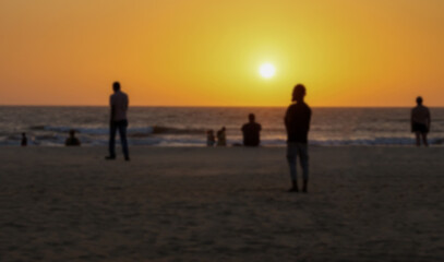Blurred silhouettes of people on the beach at sunset