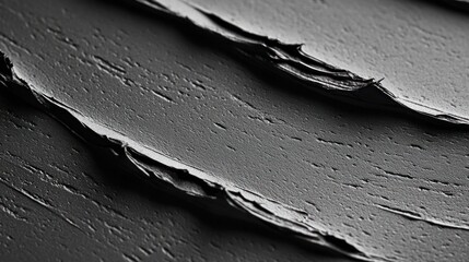 Close-up view of dark gray cosmetic product texture with streaks and cracks.