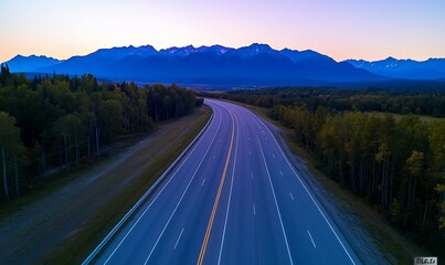 Scenic highway winding through a mountain valley at sunset.