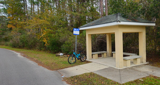 A bus stop with a bicycle chained to sign 