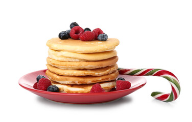 Plate of sweet pancakes with blueberries, raspberries and Christmas candy cane on white background