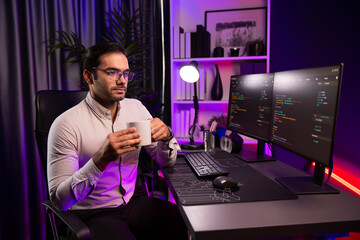 Smart IT developer drinking coffee cup while working in software development coding on pc screen, presenting program application update online website database at neon lighting cyber office. Surmise.