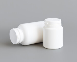 White plastic pill bottles closeup against grey, mockup. Healthcare concept, herbal supplements