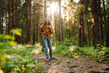 Happy young woman tourist enjoying in the beautiful forest. Hike and joy in nature.