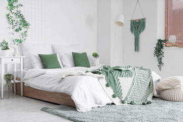 Interior of bedroom with table, pouf and green plants