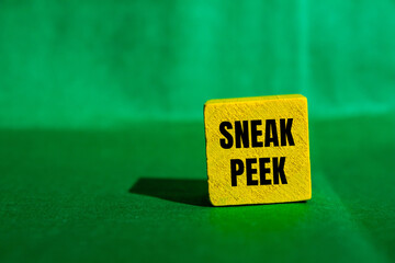 Sneak peek message written on yellow wooden cube with green background. Conceptual sneak peek...